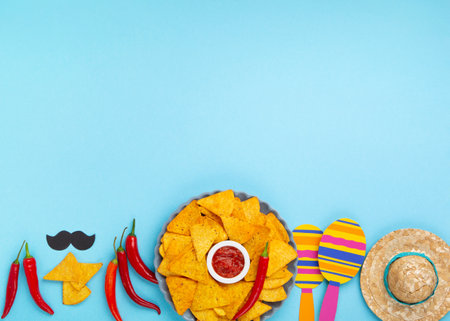Mexican fiesta background with Traditional Mexican nachos chips, chilli peppers and tomato salsa sauce on blue table. Cinco de Mayo (Fifth of May) celebration concept. Top view, copy space.の写真素材