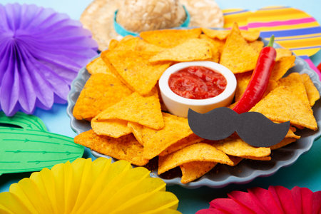Mexican fiesta background with Traditional Mexican nachos chips, chilli peppers and tomato salsa sauce on blue table. Cinco de Mayo (Fifth of May) celebration concept. Top view, copy space.の写真素材