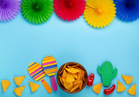 Mexican background fiesta with Traditional Mexican nachos chips, red chilli pepper, cactus and maracas on blue background. Cinco de Mayo (Fifth of May) celebration concept. Top view, copy space.の写真素材