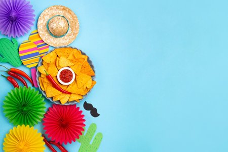 Mexican fiesta background with Traditional Mexican nachos chips, chilli peppers and tomato salsa sauce on blue table. Cinco de Mayo (Fifth of May) celebration concept. Top view, copy space.の写真素材