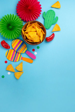 Mexican background fiesta with Traditional Mexican nachos chips, red chilli pepper, cactus and maracas on blue background. Cinco de Mayo (Fifth of May) celebration concept. Top view, copy space.の写真素材
