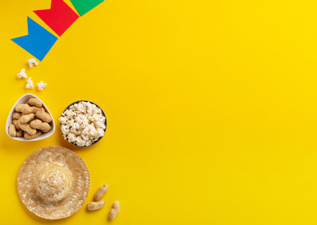 Carnival Brazilian Festa Junina Summer Festival concept. Brazilian straw hat, popcorn, peanuts and colorful flags on yellow background, top view. Design for Greeting Card, Invitation or Holiday Posterの写真素材