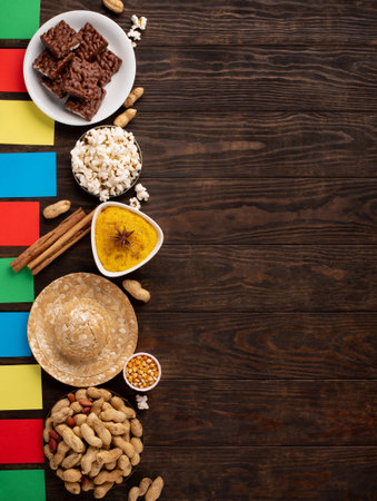 Festa Junina Summer Festival Carnival concept. Brazilian straw hat, popcorn, peanuts and colorful flags on wooden background, top view. Design for Greeting Card, Invitation or Holiday Posterの写真素材