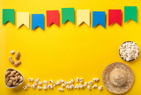 Carnival Brazilian Festa Junina Summer Festival concept. Brazilian straw hat, popcorn, peanuts and colorful flags on yellow background, top view. Design for Greeting Card, Invitation or Holiday Posterの写真素材