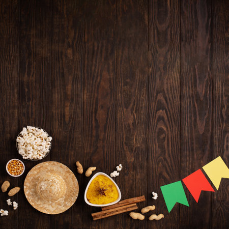 Festa Junina Summer Festival Carnival concept. Brazilian straw hat, popcorn, peanuts and colorful flags on wooden background, top view. Design for Greeting Card, Invitation or Holiday Posterの写真素材