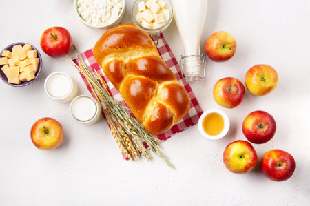 Happy Shavuot holiday card. Jewish religious holiday concept. Dairy products, fresh apples, cheese, bread, milk, cottage cheese, wheat and honey on white background. Top view, copy space.の写真素材