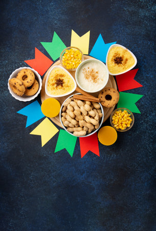 Festa Junina Summer Festival Carnival concept. Brazilian straw hat, Corn Cakes, peanuts and colorful flags on wooden blue background, top view. Design for Greeting Card, Invitation or Holiday Posterの写真素材
