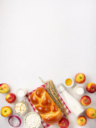 Happy Shavuot holiday card. Jewish religious holiday concept. Dairy products, fresh apples, cheese, bread, milk, cottage cheese, wheat and honey on white background. Top view, copy space.の写真素材