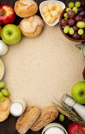 Happy Shavuot holiday card. Jewish religious holiday concept. Dairy products, fruits, cheese, bread, milk bottle, cottage cheese, wheat on dark wooden background. Top view, copy space.の写真素材