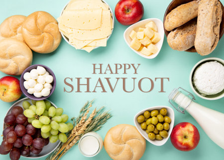 Happy Shavuot holiday card. Jewish religious holiday concept. Dairy products, fruits, cheese, bread, milk bottle, cottage cheese, wheat on blue mint background. Top view, copy space.の写真素材