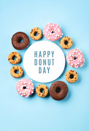 Donuts donuts with chocolate, marshmallow and sugar sprinkles on blue background, copy space. Colorful carnival or birthday party card. Happy National donut day Concept.の写真素材