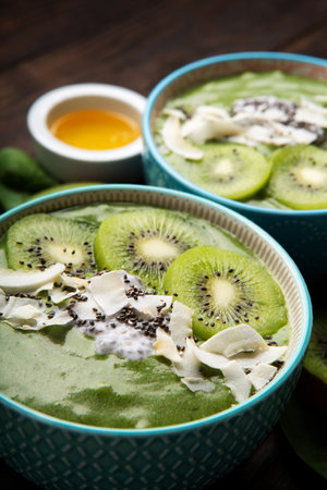 Green smoothie bowl with organic Spinach, Banana, Chia Seeds, fresh kiwi on dark wooden background. Vegan, Food and drink, healthy dieting and nutrition, alkaline, vegetarian concept.の写真素材