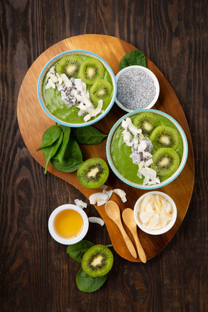 Green smoothie bowl with organic Spinach, Banana, Chia Seeds, fresh kiwi on dark wooden background. Vegan, Food and drink, healthy dieting and nutrition, alkaline, vegetarian concept.の写真素材