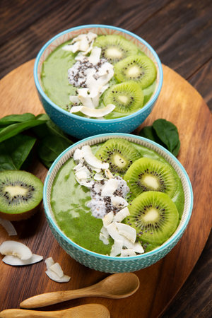 Green smoothie bowl with organic Spinach, Banana, Chia Seeds, fresh kiwi on dark wooden background. Vegan, Food and drink, healthy dieting and nutrition, alkaline, vegetarian concept.の写真素材