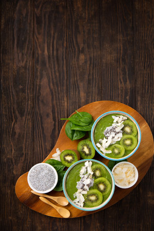 Green smoothie bowl with organic Spinach, Banana, Chia Seeds, fresh kiwi on dark wooden background. Vegan, Food and drink, healthy dieting and nutrition, alkaline, vegetarian concept.の写真素材