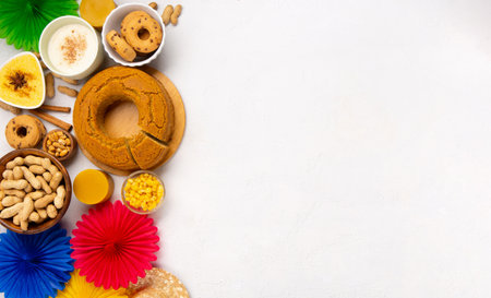 Festa Junina Summer Festival Carnival concept. Brazilian straw hat, Corn Cake, peanuts and colorful flags on white background, top view. Design for Greeting Card, Invitation or Holiday Posterの写真素材