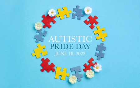 Autistic Pride Day or World Autism Awareness Day concept. Colorful puzzle, symbol of awareness for autism spectrum disorder and daisy flowers on blue background. Top view, copy space.の写真素材