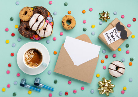 Fathers day holiday card concept with craft gift box, black mustache, cup of coffee and donuts or donuts on blue mint background, top view, copy space.の写真素材