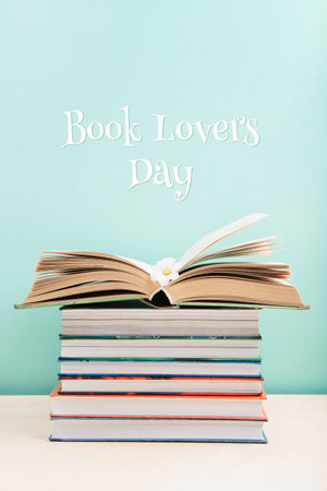 Book Lovers Day, Education concept. Open Book on wooden table and Stack of books on blue mint background. Festive card for books holiday, copy space.の写真素材