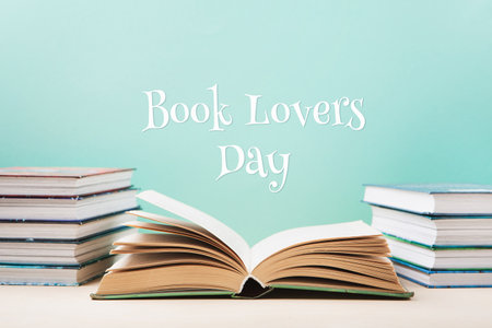 Book Lovers Day, Education concept. Open Book on wooden table and Stack of books on blue mint background. Festive card for books holiday, copy space.の写真素材