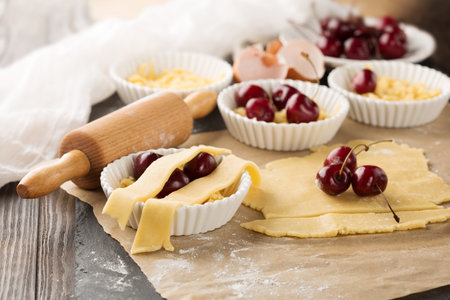 Baking cherry cake ingredients - bowl, flour, eggs and fresh berries on rustic dark background, selective focusの写真素材