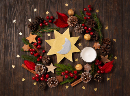 Winter solstice day, December 21. Longest night in the year concept. Sun and moon symbol, Christmas trees, pine cones, paddub branches with red berries, candle on dark wooden background, top view.の写真素材