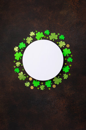 St. Patrick's Day celebration Concept. Greeting card with traditional symbols - Golden horseshoe, gold coins and clover leaves, green shamrocks on dark brown wooden background. Top view, copy space.の写真素材