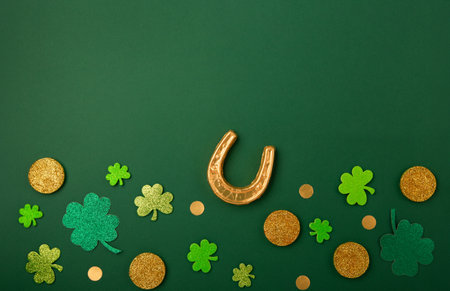 St Patricks day card with traditional symbols for irish party. Golden horseshoe, gold coins, clover leaves, green shamrocks on green background. Top view, copy space. St. Patrick's Day celebration concept.の写真素材