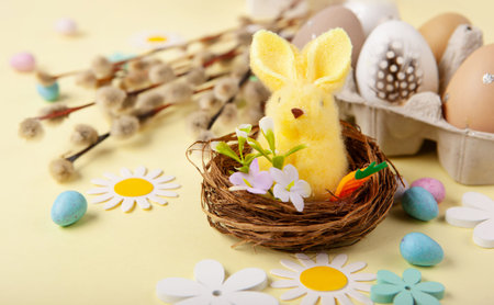 Easter spring holiday card. Playful yellow bunny, painted eggs, willow branches, paper flowers,...