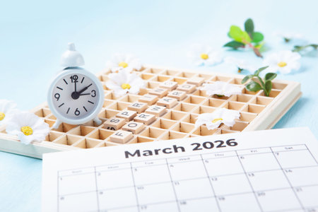 Daylight saving Time, Spring forward, Summer back concept. White Alarm Clock and Spring Daisy...