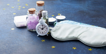 World Sleep Day concept. Sleep masks, dried lavender and classic alarm clock on dark blue wooden backgroundの写真素材