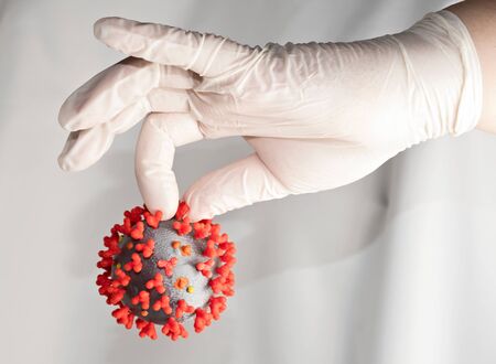 Caught coronavirus in gloved hand. Concept: Handle coronovirus with care