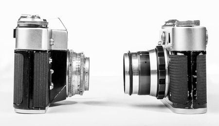 Two vintage retro camera look at each other on a white background closeupの写真素材