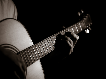 Practicing in playing guitar. Handsome young man playing guitar