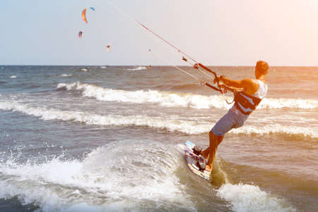 young guy kitesurfing in the ocean. sunny weather.