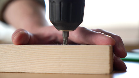 male craftsman screwing a self-tapping screw into a board with a screwdriver. close-up.の写真素材