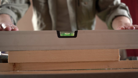 a male craftsman measures the plane with the building level of his working project