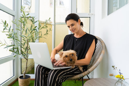 Adult Female CEO Working on Laptop with Yorkshire Terrier at Her Home. close-upの写真素材