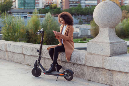 Young woman downloads the app to use the electric scooter in city street healthy life style...