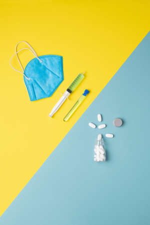 blue mask, hypodermic, pipe and a bottle of white pills, vertical top view with a diagonally divided...
