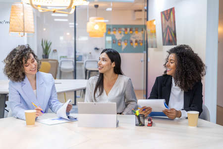 Happy business women sitting in a couch in the office and working together. Office concept.