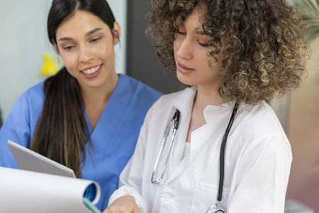 Young nurse wearing blue uniform smiling and talking with her coworker.