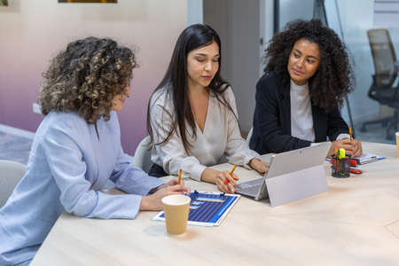 Happy business women having a meeting in the office and looking at graphics.の写真素材