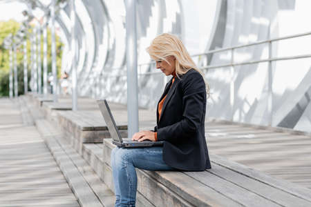 Photo with copy space of a caucasian businesswoman working with a laptop sitting in the streetの写真素材