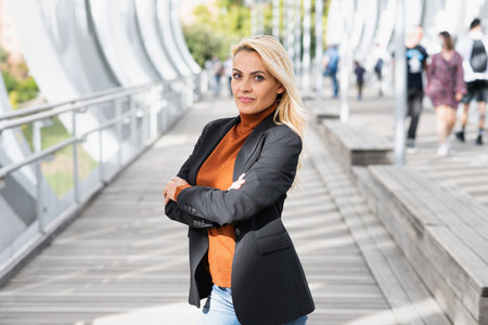 Portrait of a businesswoman posing with the arms crossed while facing the camera in a sunny dayの写真素材