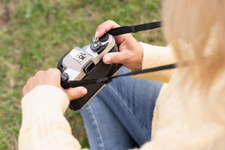 Top view photo with selective focus on the hands of a blonde woman using a camera in a parkの写真素材