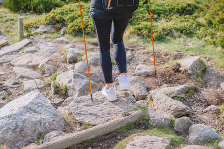 woman walking down the mountain with polesの写真素材