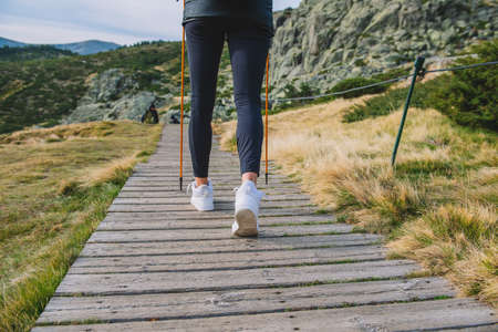 woman walking down the mountain with polesの写真素材