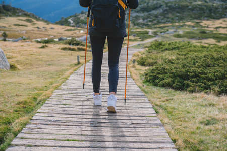 woman walking down the mountain with polesの写真素材