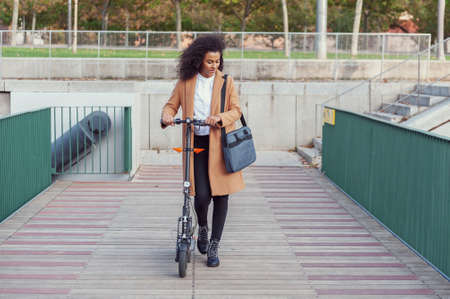woman on electric scooter with computer bag works sustainable lifestyleの写真素材